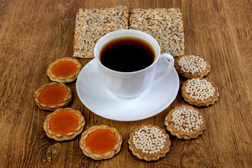 A cup of coffee and biscuits on a wooden table.
