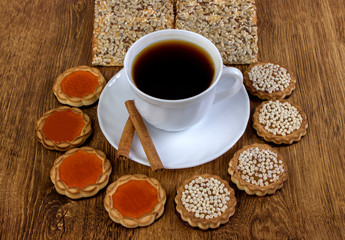A cup of coffee and biscuits on a wooden table.