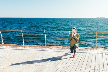 Spring morning on the beach young woman doing sports exercises against the sea