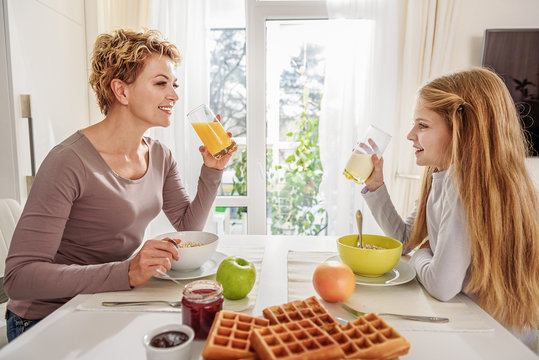 Happy mother and daughter eating cereals with milk