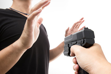 Fototapeta premium Robber with a gun robbing intimidate a man surrender. Isolated white background. Bandit steals from the male. Concept of robbery.