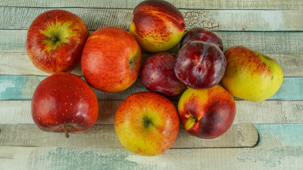 Red apples, nectarine and blue plums on wooden table