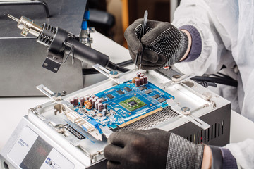 Close Up shot of male hands working with soldering iron on disassembling circuit board in mobile...