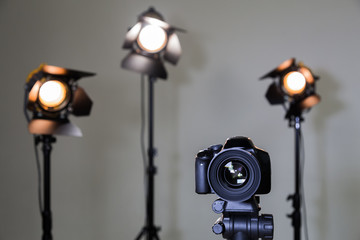 Digital SLR camera and three spotlights with Fresnel lenses. Manual interchangeable lens for filming. Shooting in the interior with artificial light. Equipment for movies.
