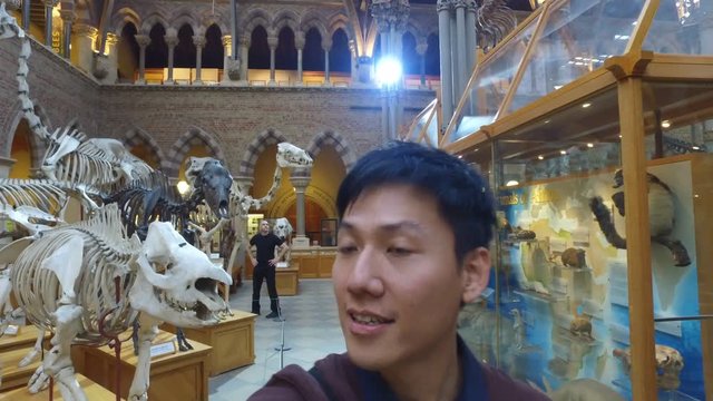  Young Asian man in museum video recording himself & the exhibits