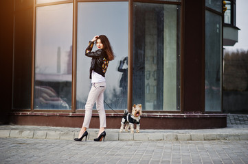 Brunette gypsy girl with yorkshire terrier dog posed against large windows house. Model wear on...