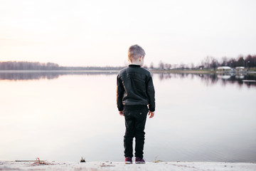 Little boy stands near the water at sunset. Conceptual photo
- 143072963