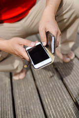 Hands holding mobile phone, wooden floor background. Feeling relax, closeup image