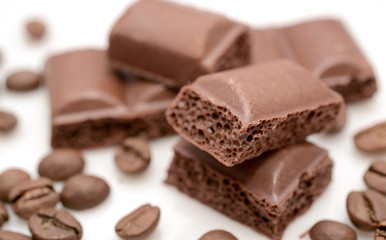Chocolate slices close-up and coffee beans on a white background.