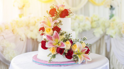Beautiful white wedding cake with red roses as decoration.