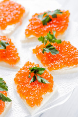 Sandwiches with salmon red caviar and herbs on white napkin. Close up image with selective focus