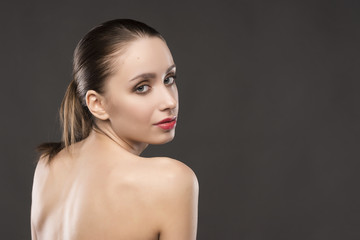 the beautiful girl naked shoulders portrait on a gray background