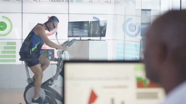  Athlete in science research program being tested by scientist in hi tec lab. 