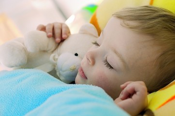 Close-up portrait of cute sleeping boy tighly holding his teddy. Child concept.