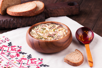 Cold Soup Okroshka in bowl and raw ingredients on wooden table