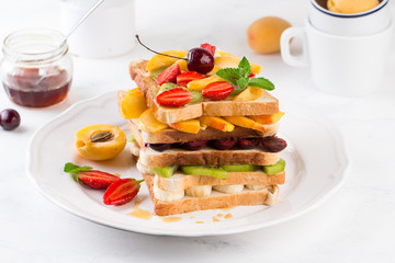 Creative healthy burger filled with sliced fresh tropical fruits, strawberries and cherry. Healthy eating concept