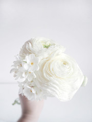 White wedding or birthday bouquet made of Persian buttercup, Ranunculus and daffodil, Narcissus, flowers. Blurred background.