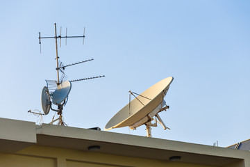 satellite dish and TV antennas on the house roof with blue sky background