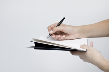 Notebook with a pen close-up in the women's hands on a white background