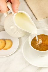 Milk poured into cup of coffee