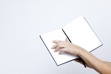 Opened notebook with white pages close-up in the women's hands on a white background