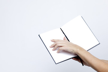 Obraz premium Opened notebook with white pages close-up in the women's hands on a white background