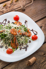 White plate with salad with shrimps and cheese 
