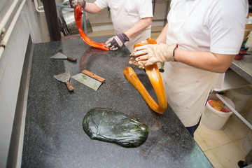 Confectioners making candy from melted colroed sugar in candy workshop
