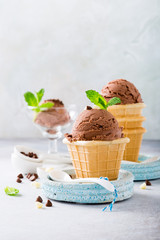 Homemade chocolate ice cream in waffle cups on blue plates on gray stone background. Healthy summer food concept with copy space.