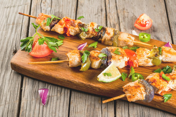Fajita chicken kebabs, with chicken meat, pepper, chili, tomatoes, onions, lime juice and herbs. In a frying pan, on a rustic wooden table. Mexican cuisine, a traditional food,