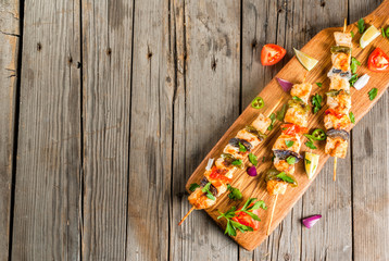 Fajita chicken kebabs, with chicken meat, pepper, chili, tomatoes, onions, lime juice and herbs. In a frying pan, on a rustic wooden table. Mexican cuisine, a traditional food,