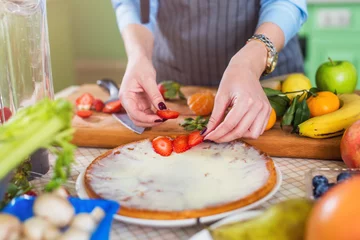 Fotobehang Woman s hands putting sliced strawberry on cake. Housewife making fruit and berry dessert © undrey