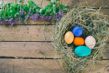 Multi-colored Easter eggs on a wooden background in the nest.