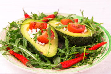 Avocado stuffed with feta cheese, arugula and tomatoes