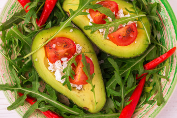 Avocado stuffed with feta cheese, arugula and tomatoes