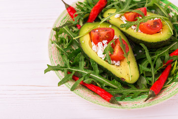 Avocado stuffed with feta cheese, arugula and tomatoes