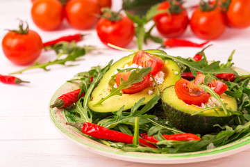 Avocado stuffed with feta cheese, arugula and tomatoes