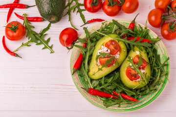 Avocado stuffed with feta cheese, arugula and tomatoes