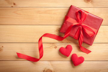 Red gift box and crochet hearts on wooden background