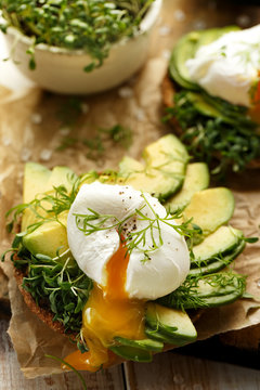 Sandwich with avocado and poached egg with addition of fresh herbs