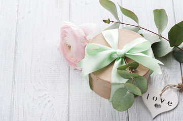 Pink ranunculus and gift box with green ribbon