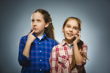 Two little Girls with cell phone are online meeting on a gray background