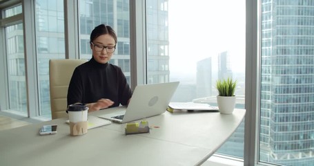 closeup Asian girl in a modern office, business correspondence using a laptop