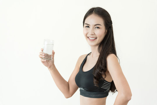 Young Asian Woman in black sportswear drinking glass of water on white isolated background. Healthy, Diet, Beauty, smiling.