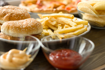 Unhealthy concept. unhealthy food: Burger, sauce, potatoes, donuts, pizza.