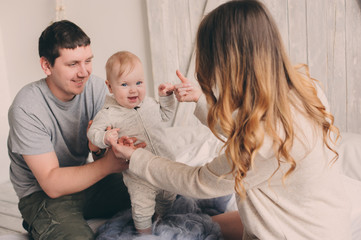 happy family playing at home on the bed. Lifestyle capture of mother, father and baby in modern scandinavian interior