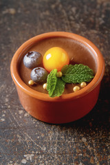Chocolate mousse with berries in a ceramic bowl. Grey dark background.