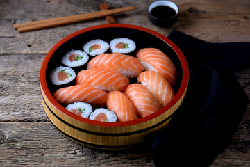 Homemade sushi with fresh salmon and cucumber on old wooden background. 