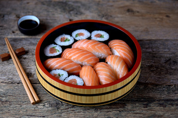 Homemade sushi with fresh salmon and cucumber on old wooden background. 