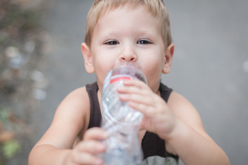 Little boy drink water from bottle outdoor